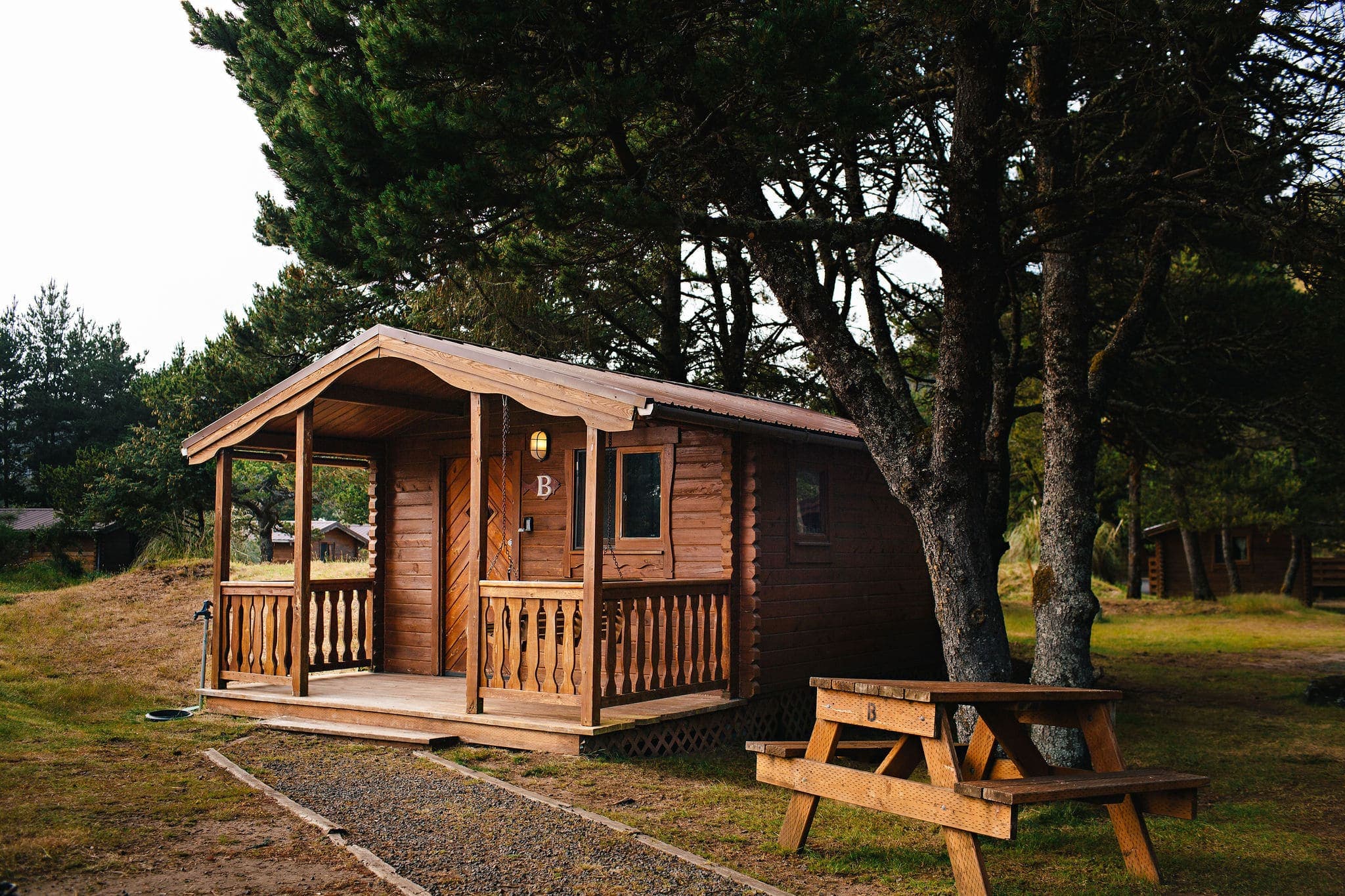 The exterior of a cabin at Harts Camp surrounded by trees with a picnic table