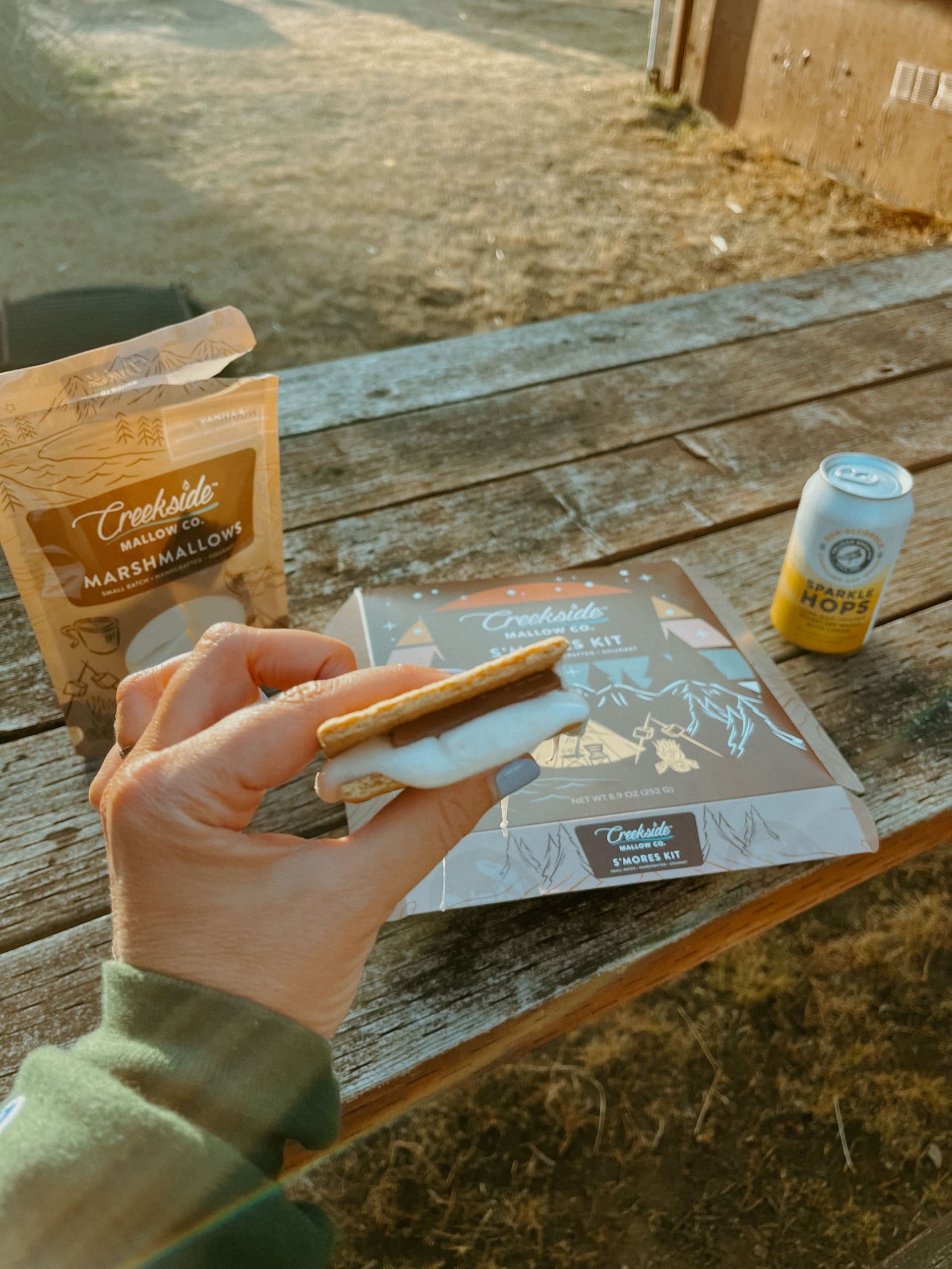 A person sitting at a picnic table holding a S'more at Harts Camp