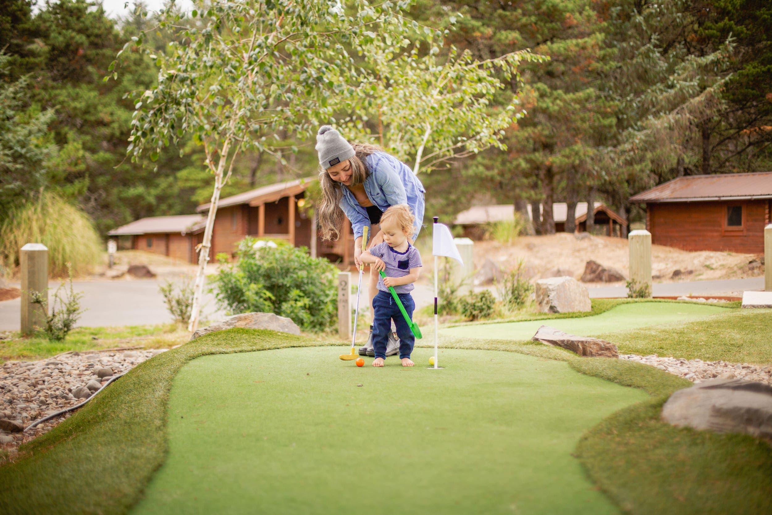 A mother playing mini putt with a small child at Cape Kiwanda