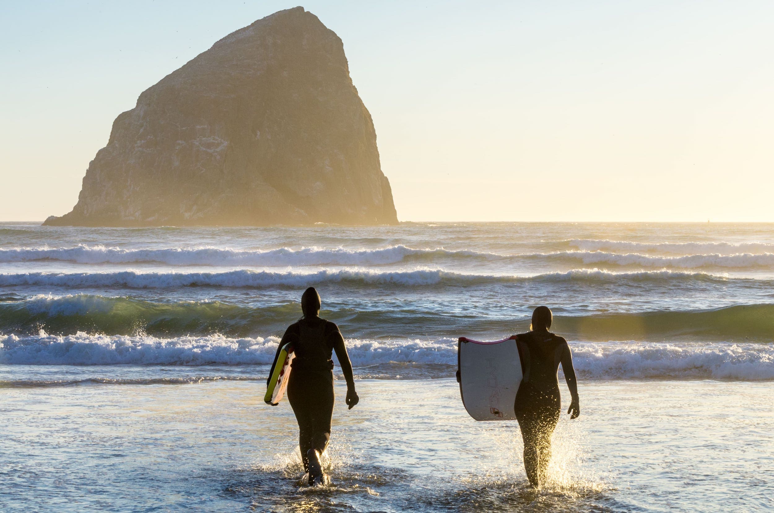 Two surfers walking into the ocean to surf near Harts Camp