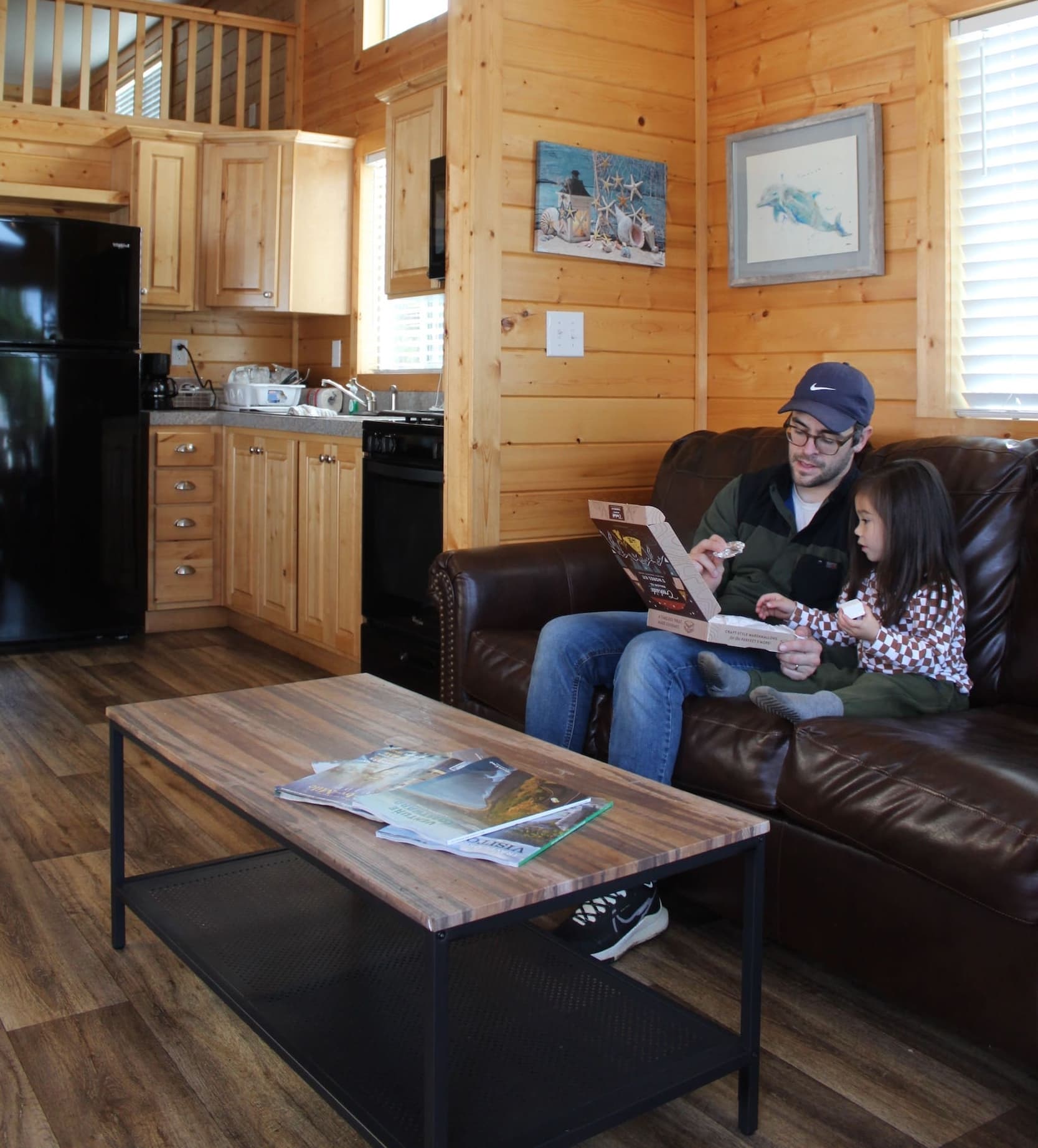 A family enjoying pizza inside a cottage rental at Hart's Camp in Pacific City, OR.