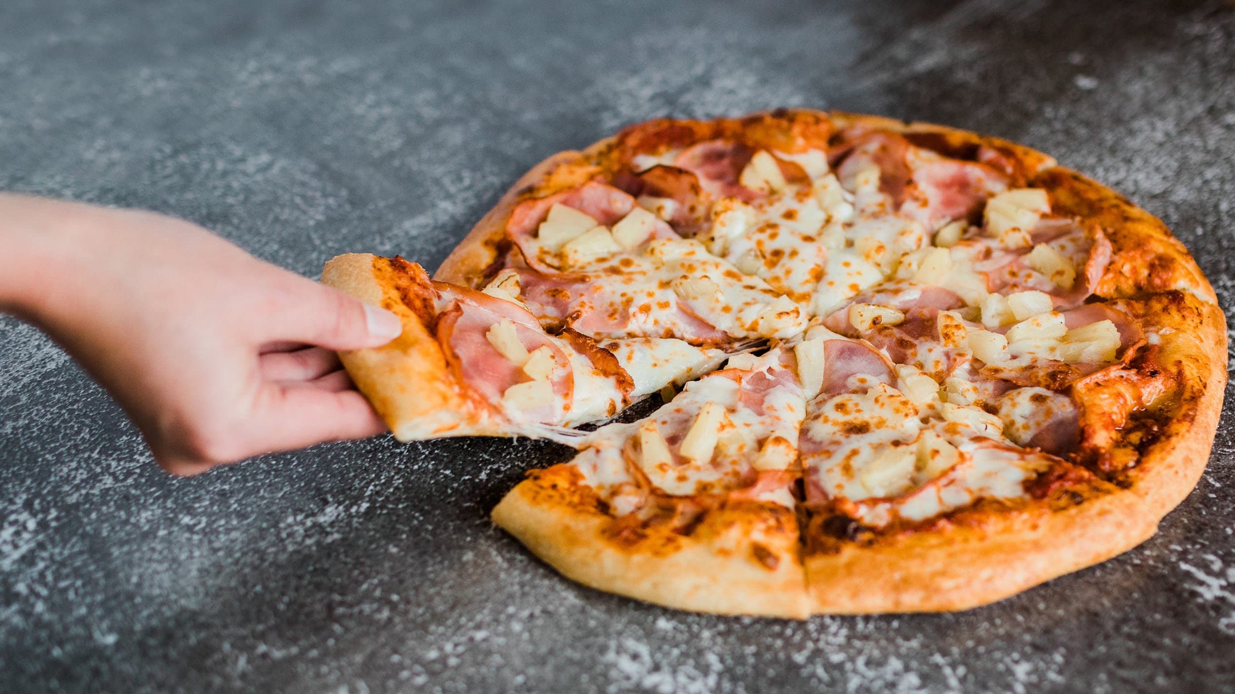 A Hawaiian pizza on a marble slab